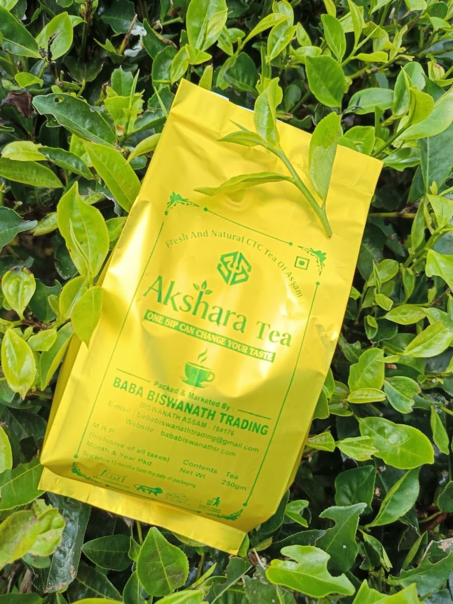 An Akshara Tea 250 g pack resting on tea bushes in leaf